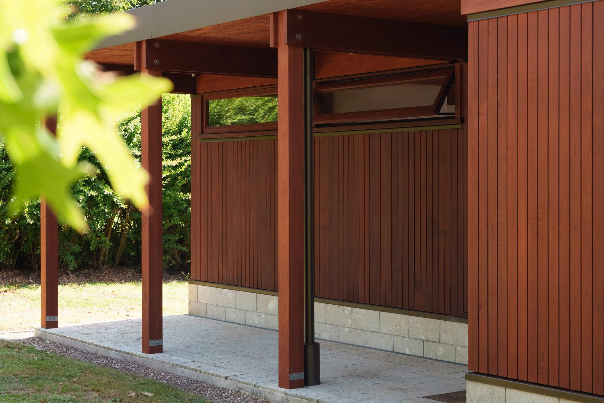 The timber pavilion veranda, cladding and posts under a deep eave.